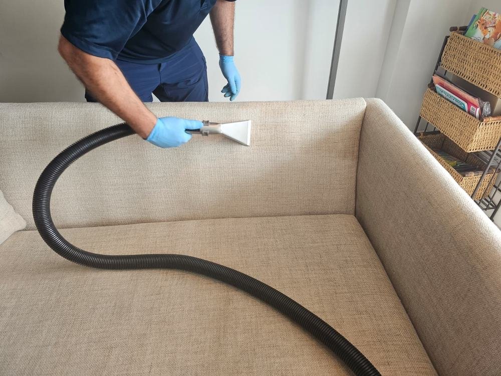 Upholstery steam cleaning with extraction hose on a sofa