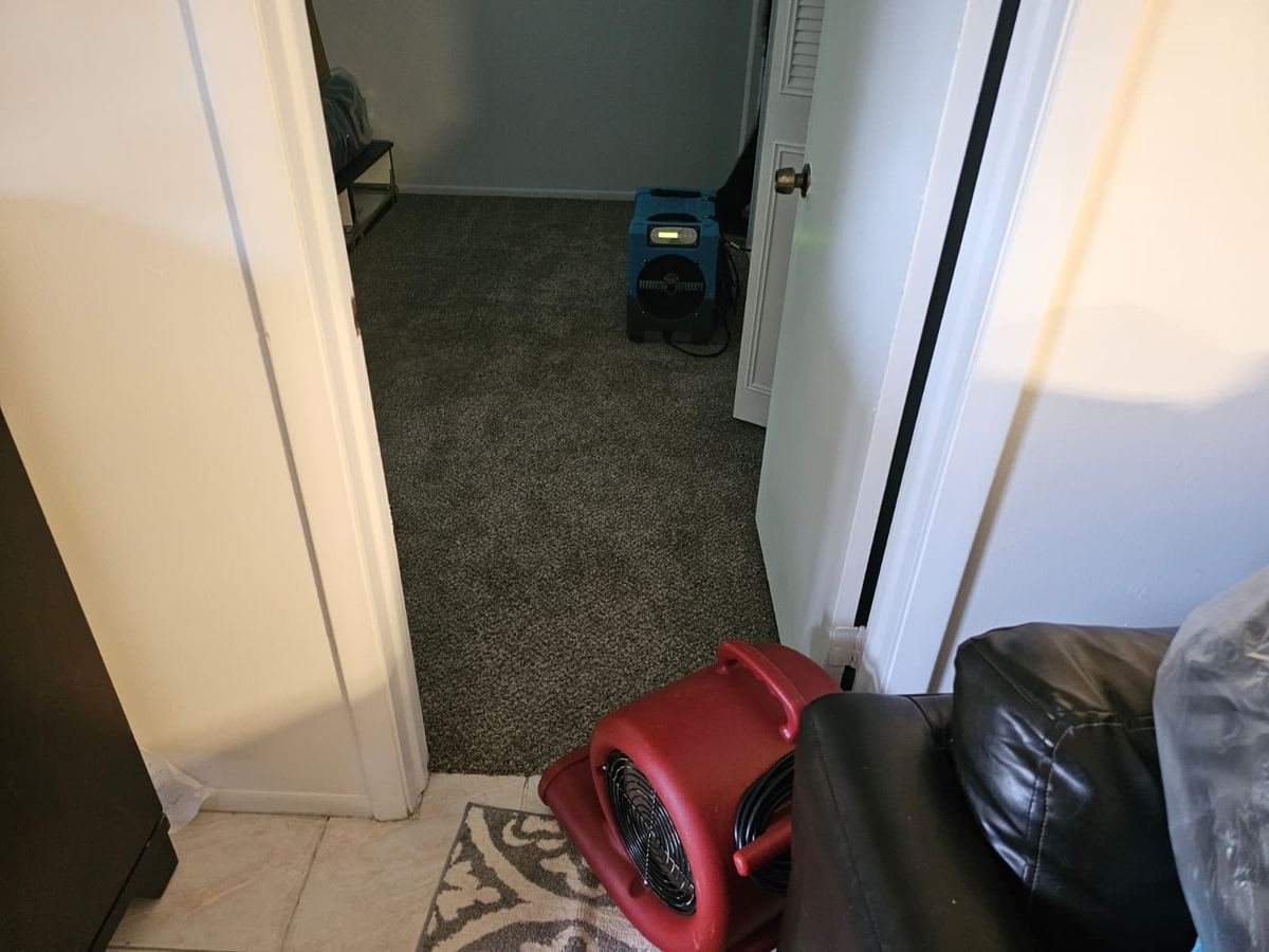 Dehumidifier and air mover drying a carpeted room after water damage