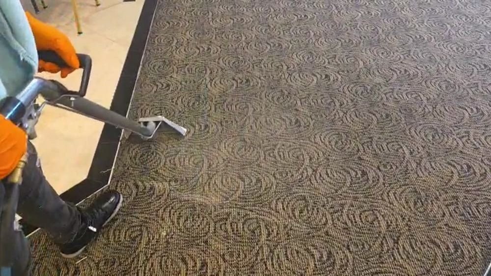 Extraction tool cleaning hallway carpet near a corner